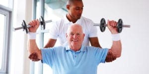 Caregiver Assisting Elderly Man Carrying Dumbells