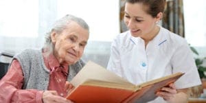 Caregiver and old woman-reading book