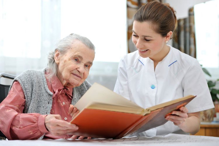 Caregiver and old woman-reading book