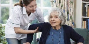 Caregiver Assisisting Old Woman with Alzheimers in Standing
